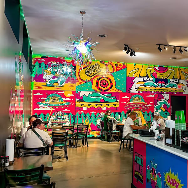 Mythical ‘Wich restaurant interior with vibrant murals, a unique chandelier, and customers dining.
